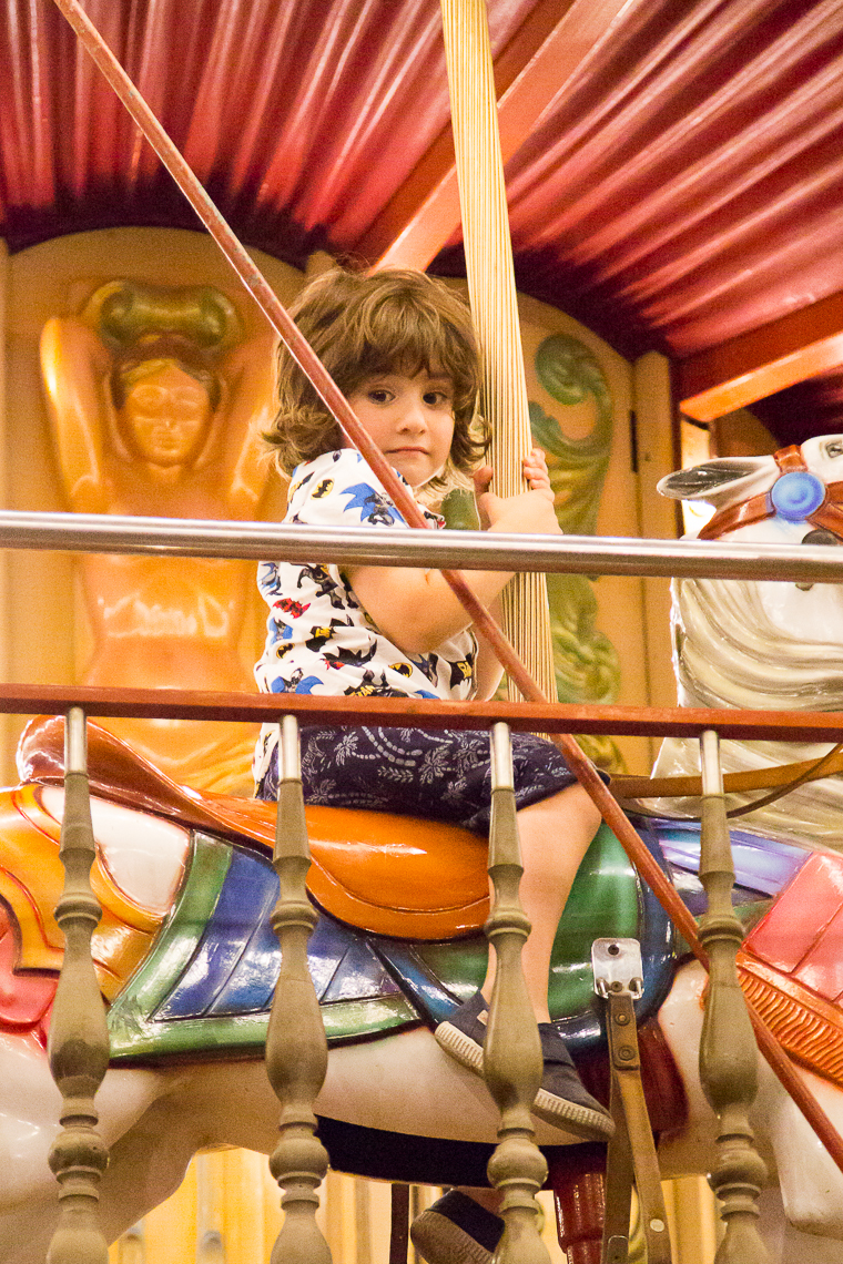 child looking unsure on a fairground carousel