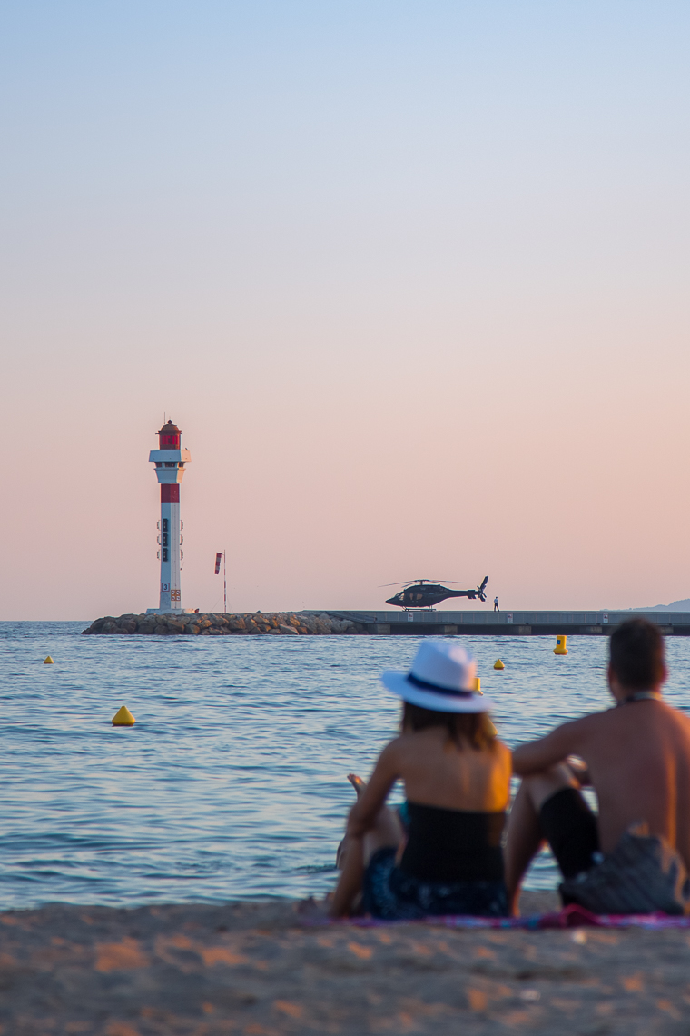 sunset in Cannes with a lighthouse and helicopter in the background. Pink skies