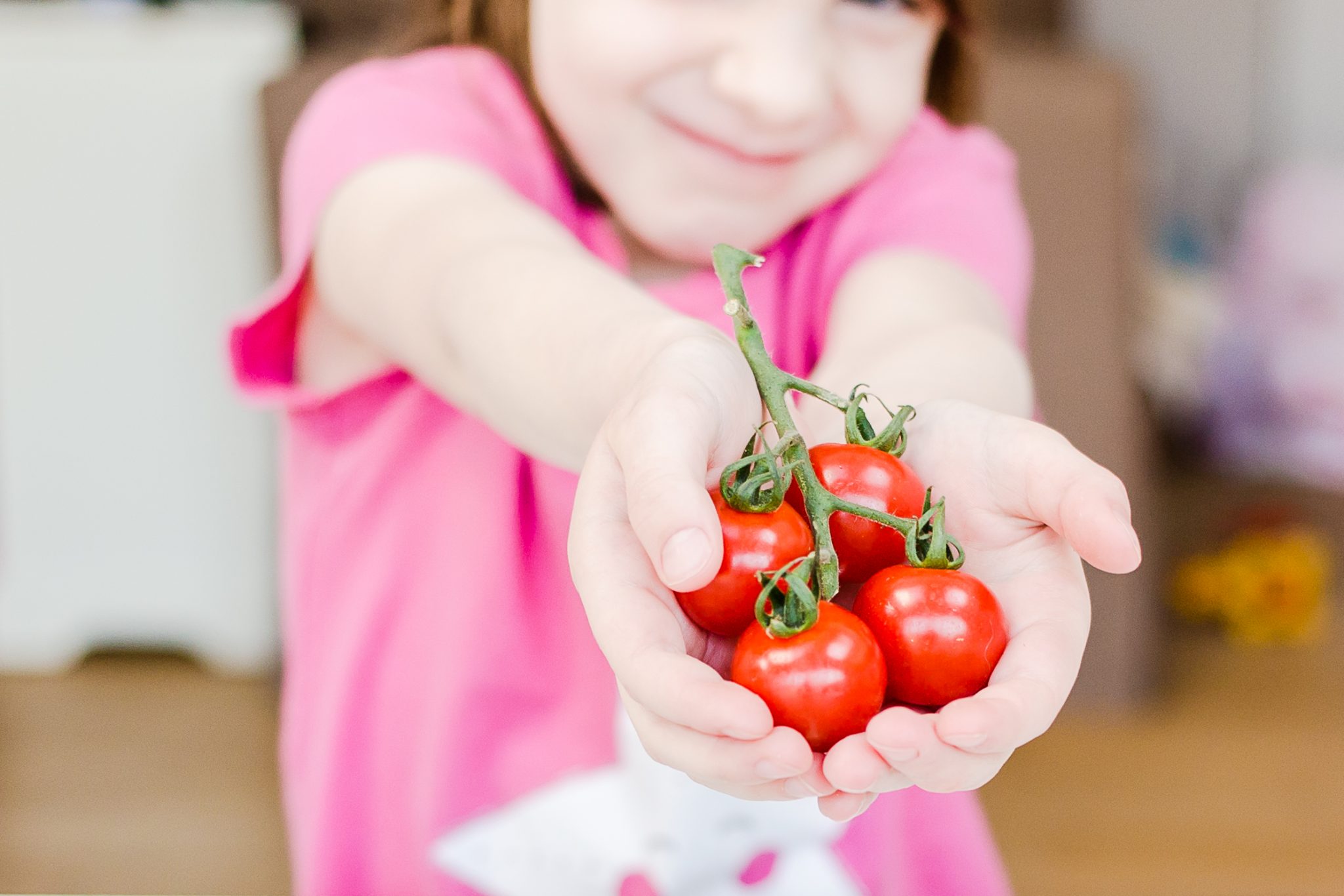 child holds out tomatoes