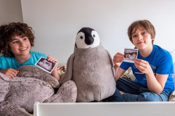 Honest Mum's sons hold up her baby girl scan photo