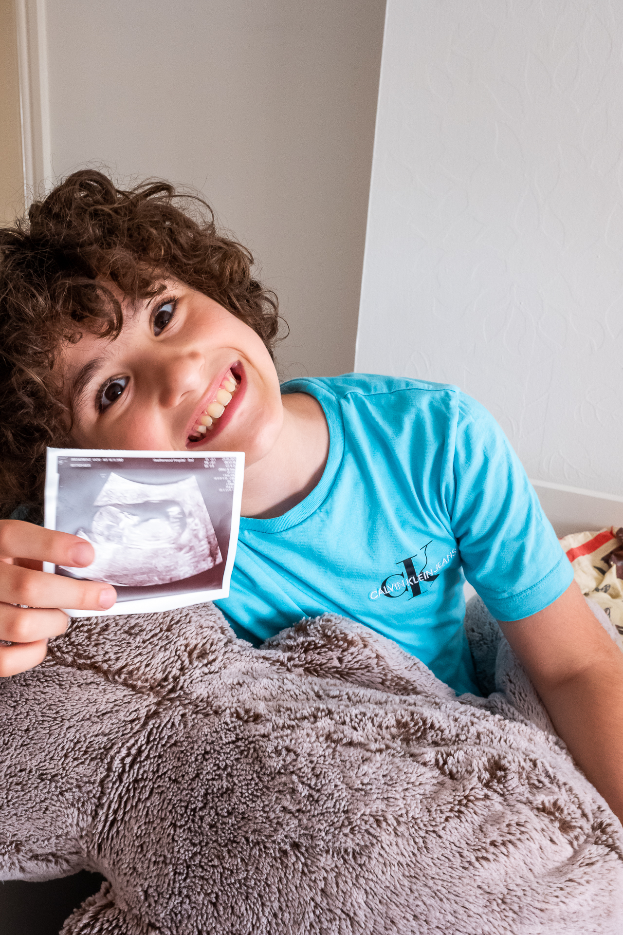 Honest Mum's son holds up the scan photo of her baby girl